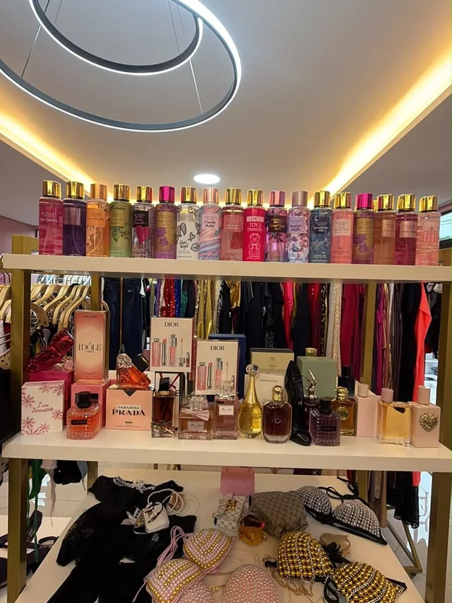 Estantería de Ruby Modas con perfumes, body splash y ropa colgada
