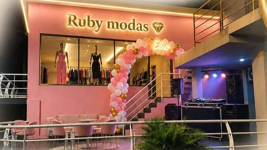 Frente de Ruby Modas: fachada rosa con el cartel dorado, la vidriera con maniquíes y un arco de globos